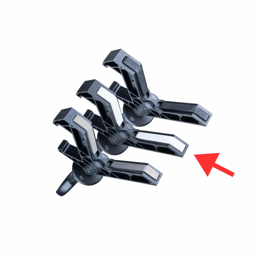 Sorte plastklemmer med geometrisk design og en rød pil, der peger på dem.