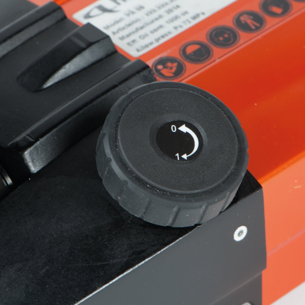 Nærbillede af Holmatro Håndpumpe justeringsknap med hvid pil og tal på sort baggrund.