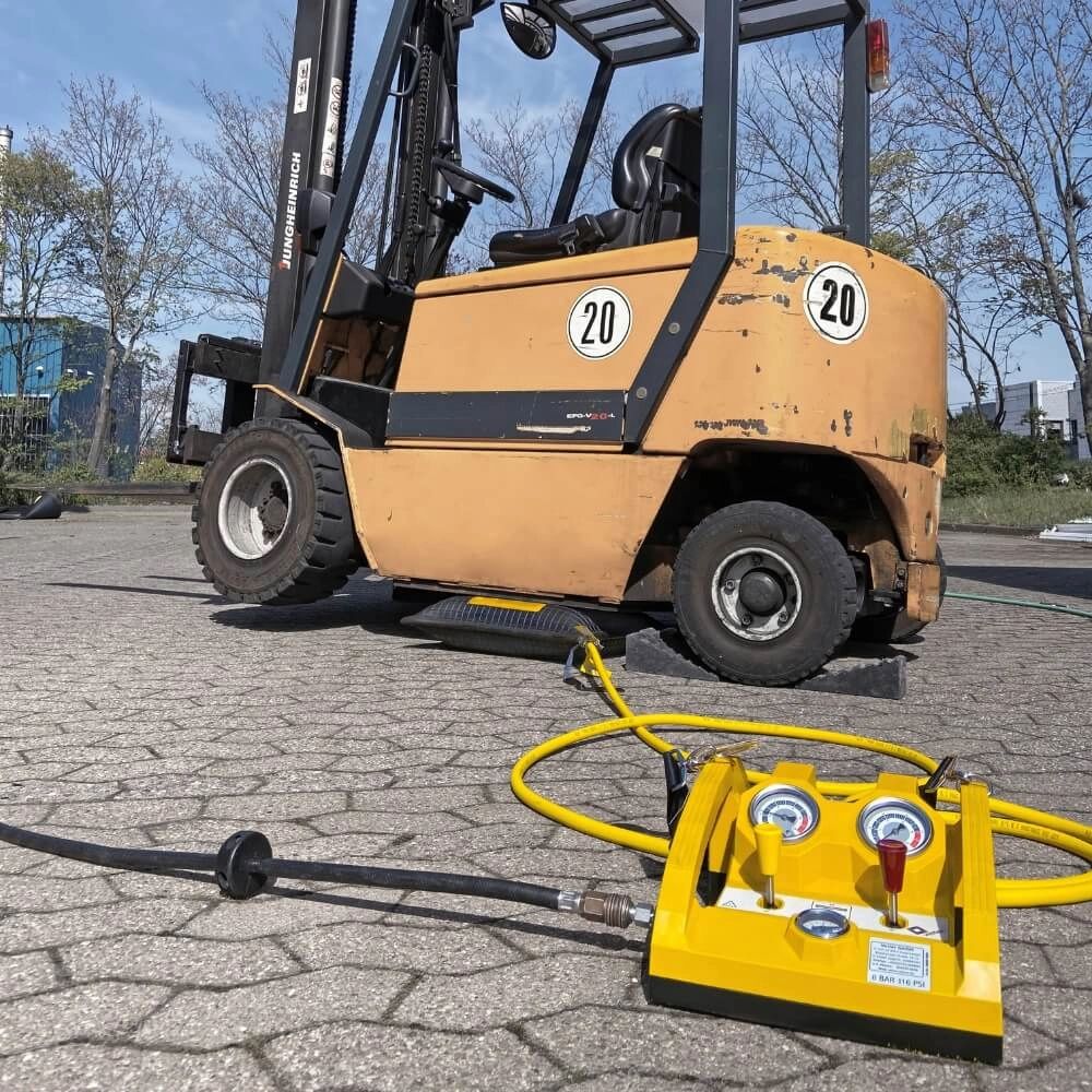 Gaffeltruck med VETTER løftepude under, forbundet til gul kontrolpanel på flisebelagt underlag.