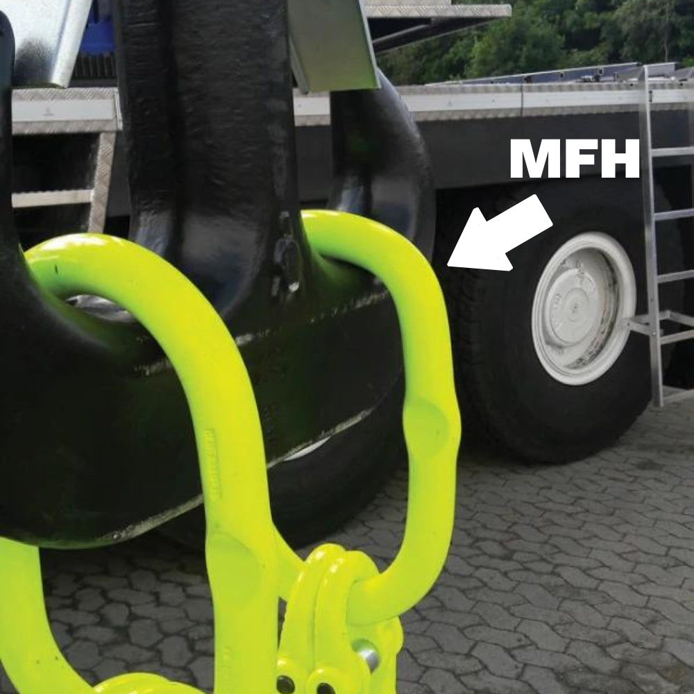 Gul oval metalring fastgjort til sort komponent, lastbildæk i baggrunden, pil og tekst "MFH".