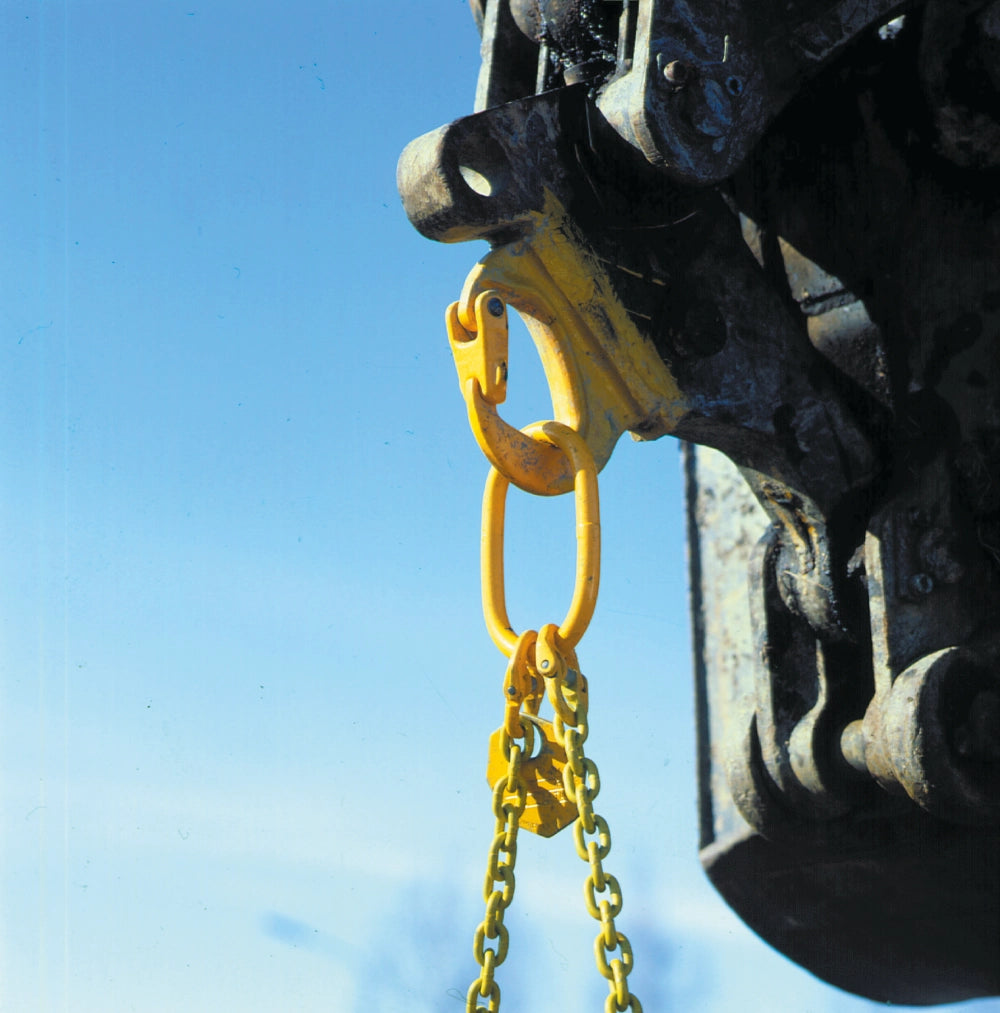 Gul krog fastgjort til maskineri med kæde, mod klar blå himmel.