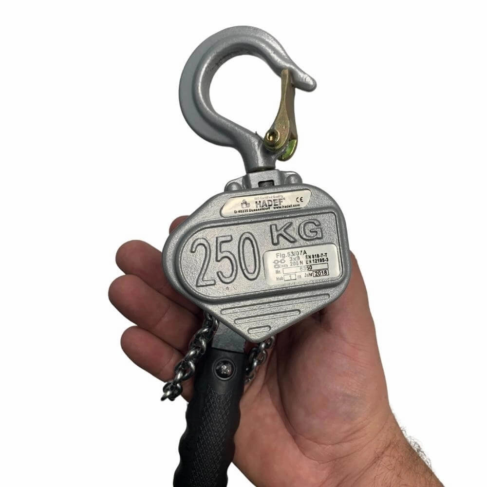Løftemekanisme med krog, kapacitet "250 KG", holdt af en hånd for skala.